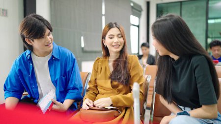 Téléchargez les photos : Jeune groupe asiatique de bonne équipe amicale assis dans le salon de départ de l'aéroport parler ensemble - en image libre de droit