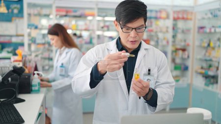 Téléchargez les photos : Pharmaciens asiatiques professionnels détenant des extraits de plantes médicinales contenant du cannabis en pharmacie - en image libre de droit