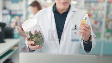 Photo for Professional Asian male pharmacists holding medicinal containing cannabis plant extracts at drugstore - Royalty Free Image