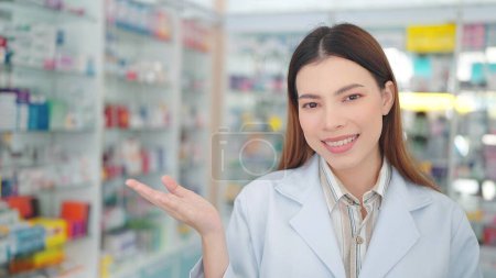 Foto de Profesional mujer asiática farmacéutico sonríe con confianza, gesto en la farmacia - Imagen libre de derechos