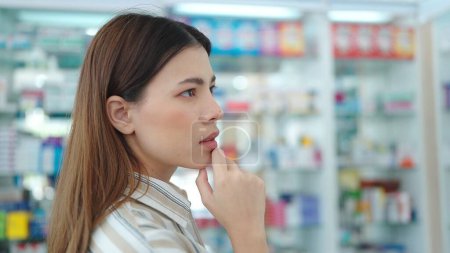 Foto de Una mujer cliente de pie y buscando productos medicamentos o suplementos en la farmacia - Imagen libre de derechos