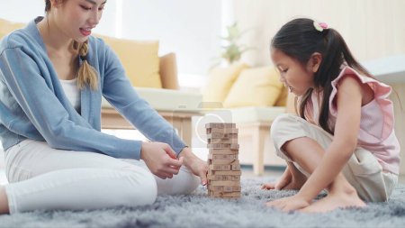 Photo for Happy little daughter having fun play stack tower wood block game with mother spending time on holiday. Activity family relationship - Royalty Free Image