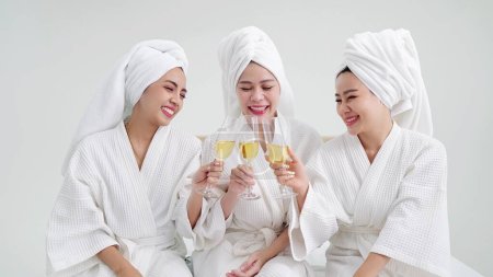 Photo for Happy young female friends in bathrobes and towels on heads holding champagne glasses. Friends together concept - Royalty Free Image
