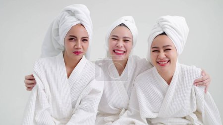 Téléchargez les photos : Portrait groupe de belles jeunes femmes asiatiques en peignoirs et serviettes sur les têtes souriant en regardant la caméra se sentir heureux - en image libre de droit