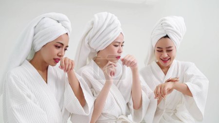 Téléchargez les photos : Groupe de jeune belle femme asiatique en peignoir blanc profiter applique crème hydratante à la peau sentant odeur parfumée. Concepts de soins de la peau - en image libre de droit