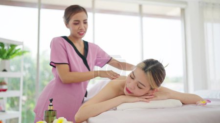Photo for Masseuse asian woman massaging back of woman in white towel lying on massage bed getting relaxing massage therapy at spa salon - Royalty Free Image