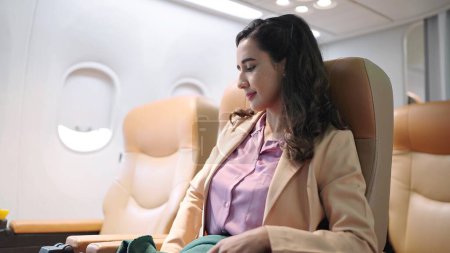 Téléchargez les photos : Hispanique latino femme d'affaires en costume assis sur confortable dans l'avion. Concept de voyage et d'affaires - en image libre de droit