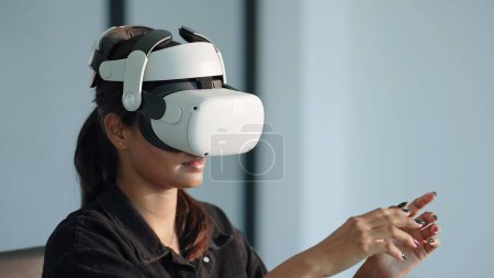 Téléchargez les photos : Jeune femme en lunettes de réalité virtuelle et la main levée touche l'air. Concept de simulation et métaverse - en image libre de droit