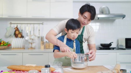 Foto de Asiático padre soltero enseñando a su hijo cocinar o hornear pasar tiempo en vacaciones juntos en la sala de cocina en casa. Comida y cocina concepto, feliz familia asiática - Imagen libre de derechos