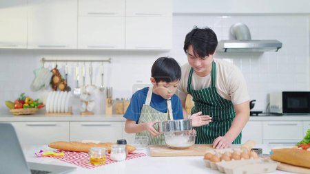Photo for Asian single father teaching son cooking or baking spending time on holidays together in kitchen room at home. Food and cuisine concept, Happy asian family - Royalty Free Image