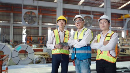 Photo for Team of asian engineers men wearing safety hard hat and vest standing with arms crossed at industrial factory. looking around at factory. Teamwork concept - Royalty Free Image