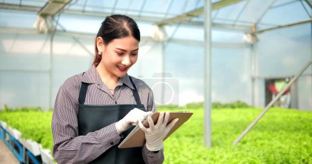 Photo for Young Asian woman farmer or owner of organic vegetable farm holding tablet for checking quality of organic lettuce. Business agriculture technology concept - Royalty Free Image