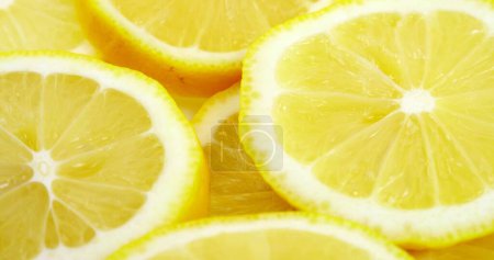 Téléchargez les photos : Fermer les tranches de citron frais motif fond. Citron coupé en deux au-dessus. Tranches de citron juteuses et lumineuses. Texture fond, motif - en image libre de droit