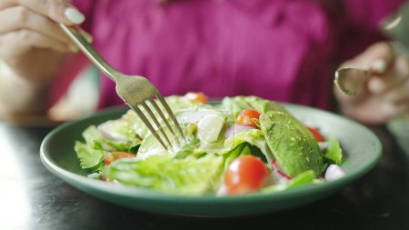 Téléchargez les photos : Concept de nourriture saine, Femme aime manger de la salade d'avocats. Fermer la salade verte avec de l'avocat tranché. Aliments végétaliens sains - en image libre de droit