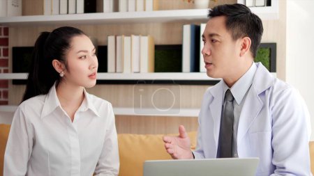 Photo for Asian doctor man visited patient woman and using laptop to check up health at hospital. Woman patient consulting health problem and symptoms with doctor. Health care service - Royalty Free Image