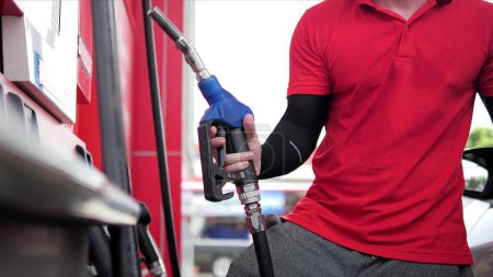 Photo for Close up hands of gas station worker holding nozzle to refueling standing at gas station. Transportation power business concept - Royalty Free Image
