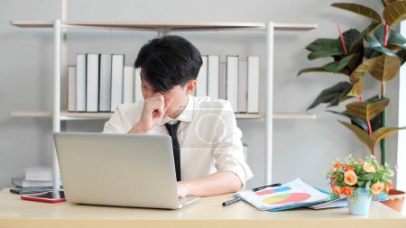 Photo for Young Asian man tired eyes from hard work. Young man tired feeling eyestrain stressed working from laptop. Suffers eyesight problem after using laptop for working long time - Royalty Free Image