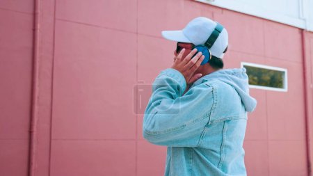 Téléchargez les photos : Heureux jeune homme asiatique en jeans portant des écouteurs écoutant de la musique appréciant la chanson préférée. Style de vie et concept de bonheur - en image libre de droit