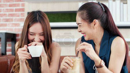 Foto de Dos jóvenes amigas asiáticas disfrutan hablando juntas en la cafetería de vacaciones. Mujer joven y feliz charlando con alegría divertida, reír, relajarse y sonreír. Mujer concepto de estilo de vida - Imagen libre de derechos