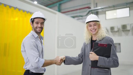 Foto de Ingenieros felices colegas hombres y mujeres que se dan la mano juntos de éxito trabajando en la fábrica de fabricación de la industria. Concepto de trabajo en equipo - Imagen libre de derechos