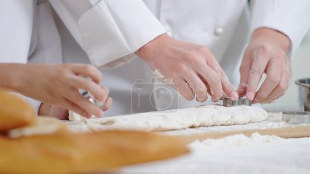 Téléchargez les photos : Fermer les mains du chef cuisinier ou cuire ensemble. Appuyez sur le moule en acier inoxydable sur la pâte. pour faire diverses formes. Concept de cuisson ou de cuisson - en image libre de droit