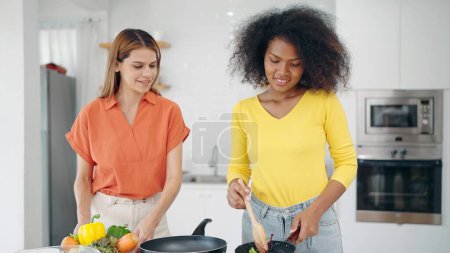 Téléchargez les photos : Heureuses femmes lesbiennes couple aiment cuisiner ensemble dans la salle de cuisine à la maison. Deux femmes passent du temps à cuisiner ensemble le week-end dans la salle de cuisine. Concept de relation Lgbt - en image libre de droit