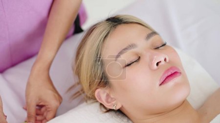 Téléchargez les photos : Gros plan sur le visage d'une belle femme allongée sur un lit de spa attendant un traitement facial au salon de spa. Soins de beauté sur le visage, Concept de beauté - en image libre de droit