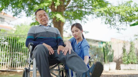 Photo for Young asian woman physical therapists helping elderly male patient in wheelchair making leg and knee physiotherapy. Symptom knee pain of elderly - Royalty Free Image