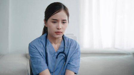 Photo for Tired depressed young asian woman nurse suffer after hard working. Exhausted sad woman doctor feels burnout stress. Physician burnout - Royalty Free Image