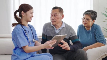 Téléchargez les photos : Asiatique infirmière soignante décrit l'état de santé du vieux couple âgé sur tablette. Soins infirmiers à domicile et soins de santé aux personnes âgées. Concept de soins aux personnes âgées - en image libre de droit