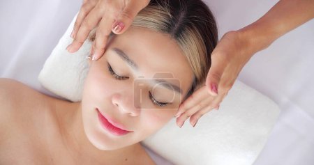 Foto de Cerca de la cara de hermosas mujeres asiáticas recibiendo tratamiento de masaje facial en la clínica de belleza. Tratamiento de belleza en la cara. Belleza masaje facial, concepto de cuidado de la piel - Imagen libre de derechos