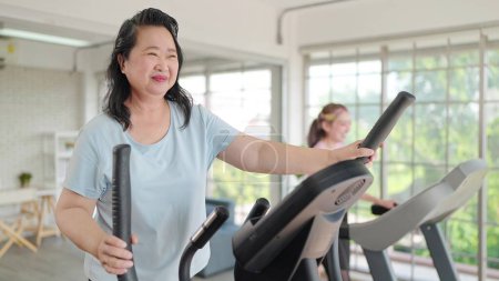 Photo for Asian elderly women exercising on the machine in living room at home. Mature woman enjoy doing exercising on treadmill for well being slimming weight. Elderly lifestyle concept - Royalty Free Image