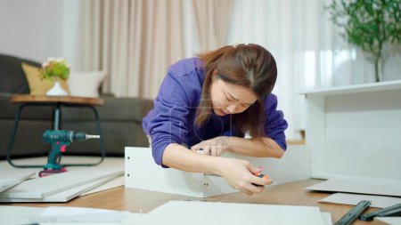 Photo for Young asian women using tightens screw for assembling new furniture by herself at home. Assembling furniture concept - Royalty Free Image