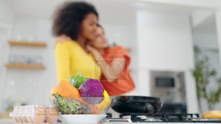 Foto de Cerrar la cesta de verduras en la mesa en la sala de la cocina y el fondo es feliz pareja de mujeres lesbianas pasar tiempo juntos y momento de amor. Pareja lesbiana abrazándose juntos - Imagen libre de derechos