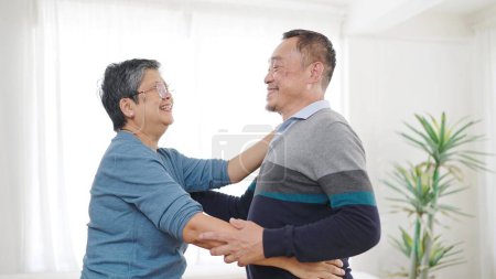 Téléchargez les photos : Heureux couple de personnes âgées asiatiques aiment danser ensemble dans le salon à la maison. Doux couple âgé profiter moment d'amour. Retraite style de vie de couple asiatique concept senior - en image libre de droit