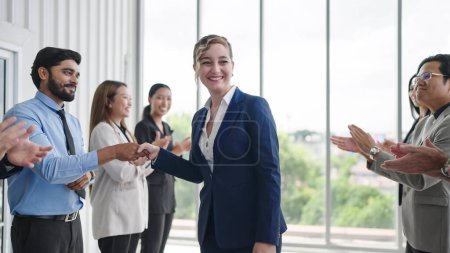 Photo for Group of business people applauding to caucasian woman leader congratulation business achievement. Diverse employees clapping and shaking hands welcoming new manager. Applauding and cheering - Royalty Free Image