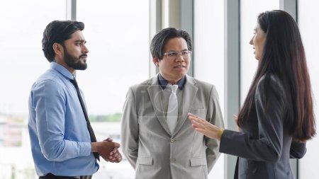 Photo for Three colleagues talking and discussing about work at office. Group of businesspeople talking to each other while standing at modern office. Business meeting - Royalty Free Image