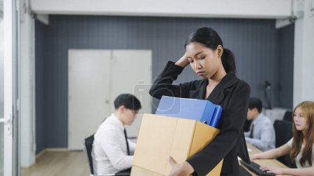 Téléchargez les photos : Femme d'affaires asiatique emballant ses affaires dans une boîte en carton après avoir été virée. Chômage, licenciement - en image libre de droit