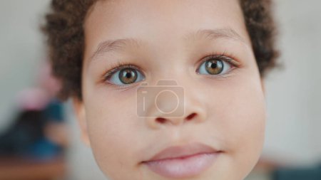 Foto de Primer plano retrato pequeño chico afroamericano sonrisa posando mirando a la cámara. Alegre afroamericano pequeño lindo chico estudiante. Concepto de alumno. Regreso al concepto escolar - Imagen libre de derechos