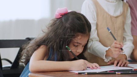 Photo for School kids writing in notebook during lesson in classroom. Little girl pupil writing lesson in classroom. Back to school concept, Education and learning concept - Royalty Free Image