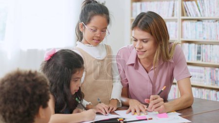Photo for Female teacher helping school kids in classroom. Elementary woman teacher teaching students doing the lesson in classroom. Education knowledge concept - Royalty Free Image