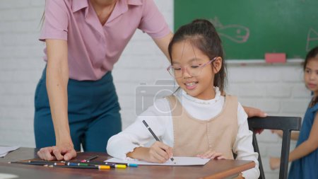 Photo for Female teacher helping school kids in classroom. Elementary woman teacher teaching students doing the lesson in classroom. Education knowledge concept - Royalty Free Image