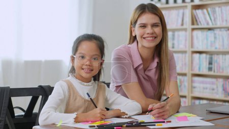Photo for Happy schoolgirl and young women teacher smiling to camera in classroom at school. Teacher woman and little girl pupil. Back to school concept, Education and learning concept - Royalty Free Image