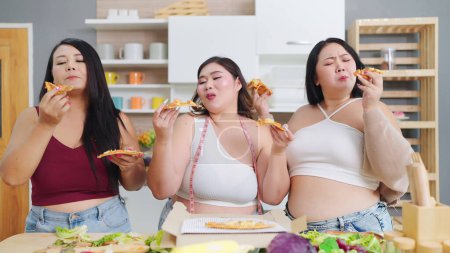 Téléchargez les photos : Groupe de joyeux asiatiques plus les femmes de taille amis aiment manger de la pizza ensemble. Femmes joufflu amis avec se sentir bien tout en mangeant de la pizza. Acceptation corporelle, Concept positif corporel - en image libre de droit