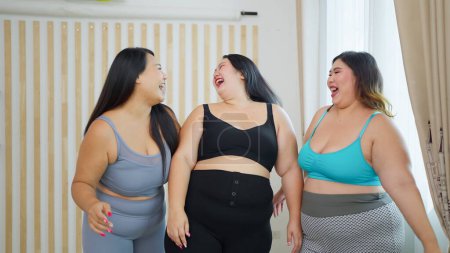 Téléchargez les photos : Groupe joyeux de femmes asiatiques plus la taille des amis en vêtements de sport profiter de parler ensemble avant l'exercice. Joyeuses amies joufflues. Concept positif du corps - en image libre de droit