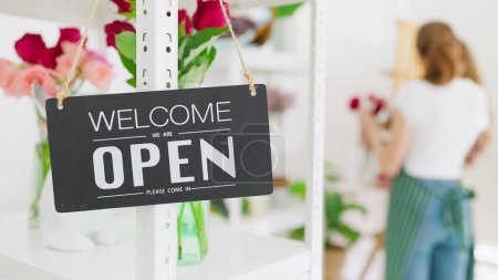Photo for Signboard "Open" on the glass door at flower shop. Text on black signboard "Welcome Open" at flower shop. Small business. Opening store. Starting workday - Royalty Free Image