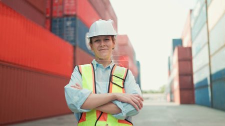 Photo for Smiling portrait of beautiful caucasian woman foreman in hardhat and safety vest standing with arms crossed looking at camera. Inspector or supervisor in container terminal - Royalty Free Image