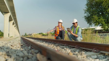 Photo for Two engineers in safety uniform and helmet using tablet discussion and inspection construction process railway. Two engineer working on railway together. Teamwork concept - Royalty Free Image