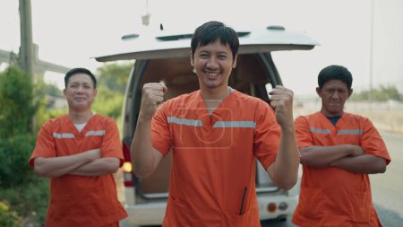Téléchargez les photos : Excité trois asiatique homme sauvetage équipe en uniforme faire une pose gagnante et debout, regardant caméra. Gagnant excité posant avec les bras levés. Travail d'équipe, succès, concept de célébration - en image libre de droit