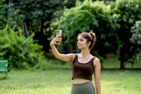 Nett aussehende Frau im Fitnessstudio-Outfit macht Selfie im Park nach dem Training am Morgen